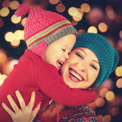 Little girl hugging her mother while they look at Christmas lights